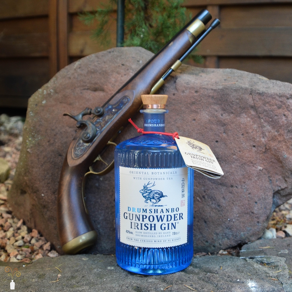 Eine Flasche des Drumshanbo Gunpowder Irish Gin mit alter Pistole zur Dekoration